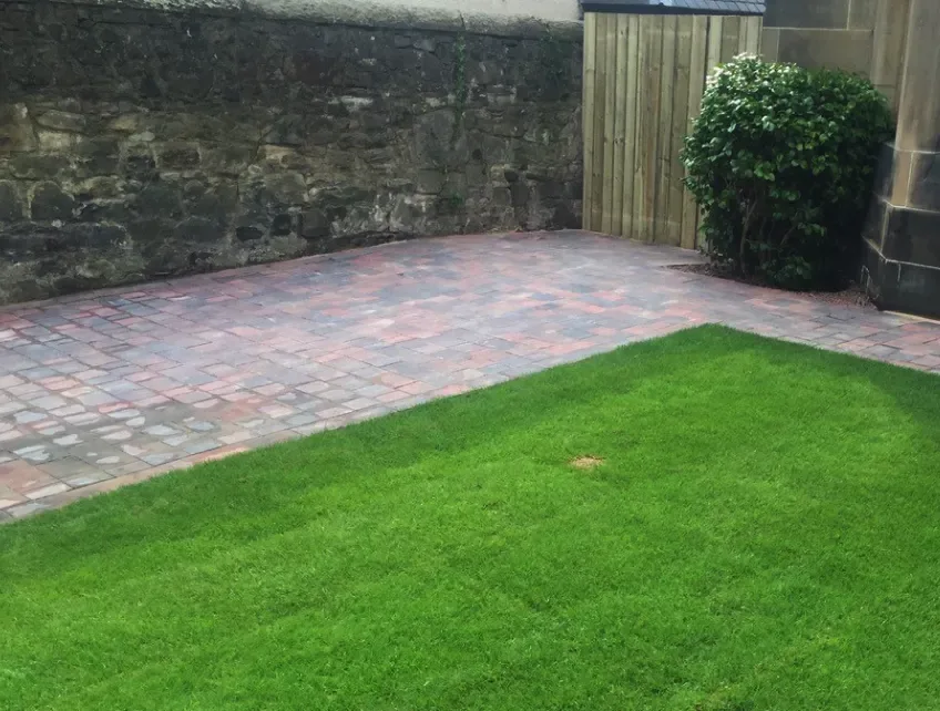 Block paving patio with neat cuts around a planted bed