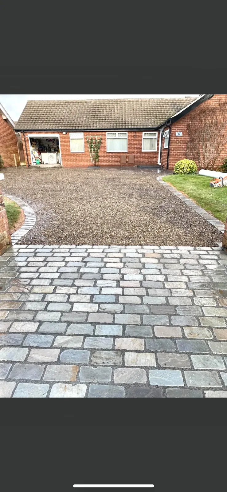 Gravel driveway with block edge restraints alongside a house