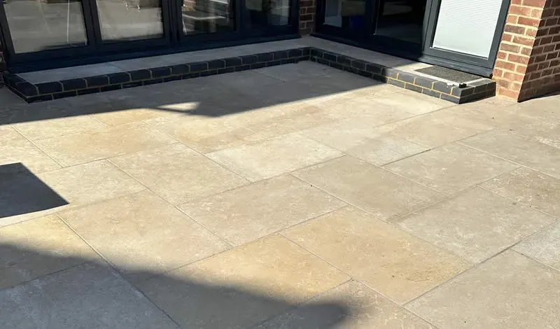 Cream large-format porcelain patio slabs laid across a rear terrace