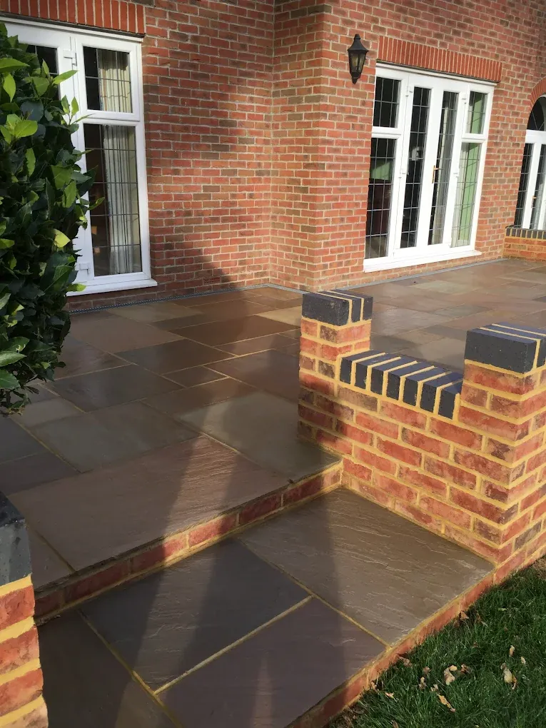 Sandstone terrace with brick-faced steps leading up to a rear door