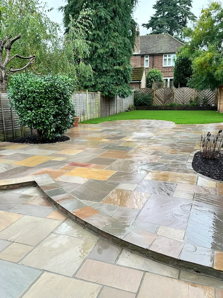 Sandstone patio curving around a shaped lawn