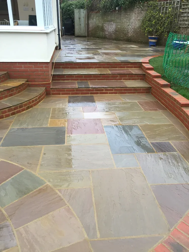 Sandstone patio with shallow steps rising to a lawn